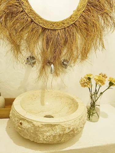 a large stone bowl with flowers in a vase at Casa dos Bonitos in Santa Susana