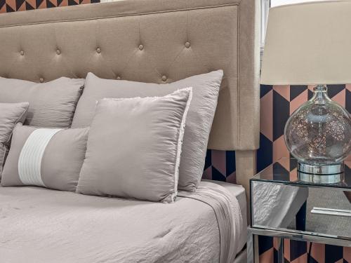 a bed with white pillows and a table with a lamp at Casa Ladrillo - House of Bricks in Calgary