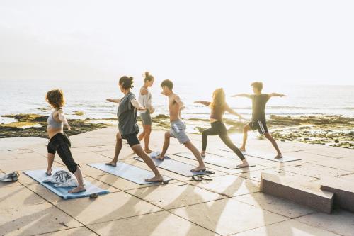 a group of young people doing yoga on the beach at Tamaran House in Las Palmas de Gran Canaria