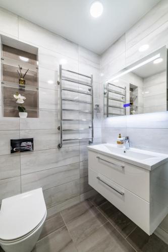 a white bathroom with a toilet and a sink at Amber Apartments in Šiauliai