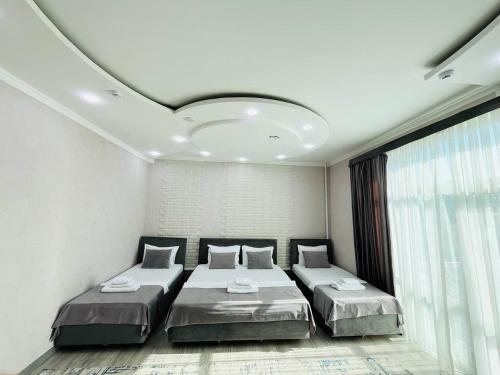 a bedroom with two beds and a large window at Hotel Shosh Boutique in Tashkent