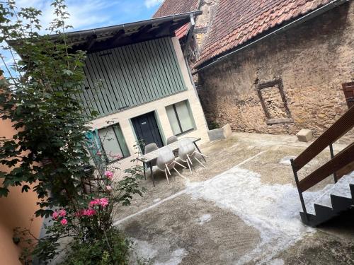 un patio avec une table et des chaises à côté d'un bâtiment dans l'établissement Gîte Aux Quatre Vents avec Terrasse, à Rouffach