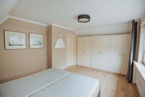 a bedroom with a white bed and white cabinets at Ferienwohnung Krysiak in Hille