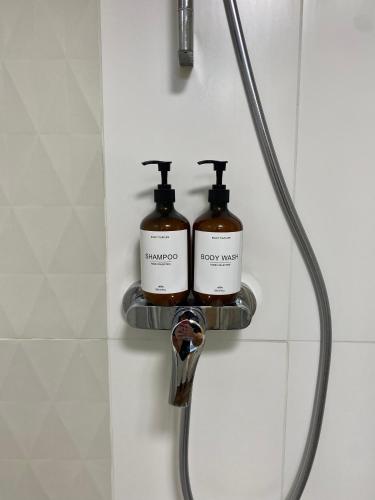 deux bouteilles de savon assises sur une étagère dans une douche dans l'établissement Maison De Charme - 2 Suites Deluxe - Brive Centre Historique, à Brive-la-Gaillarde