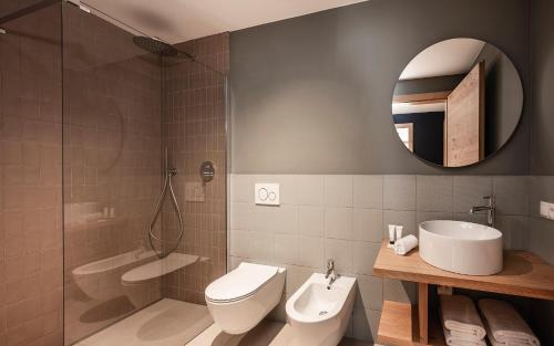 a bathroom with a toilet and a sink and a mirror at The Post Mountain Residence in Dobbiaco