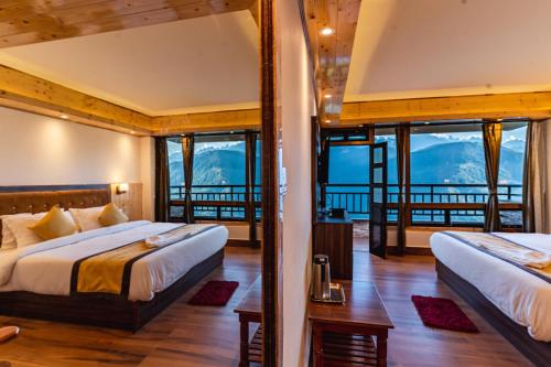 two beds in a room with mountains in the background at The Golden Retreat Hotel in Pelling in Pelling