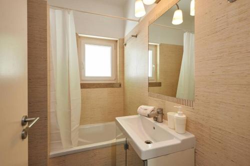 a white bathroom with a sink and a mirror at Central Oasis Apartment in Cascais