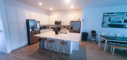 a kitchen with a white counter and bar stools at Magic Kingdom Villa - Private Master Bedrooms in Kissimmee