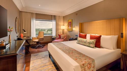 a hotel room with a large bed and a desk at The Leela Hyderabad Banjara Hills in Hyderabad