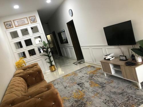 a living room with two couches and a flat screen tv at Ammara Homestay PD in Kampong Tanah Merah