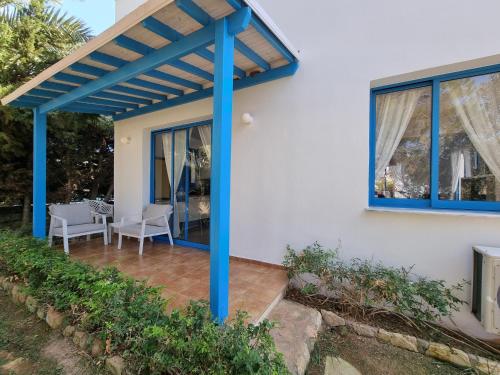 a pergola on a house with a table and chairs at Olive Beach Villa in Peyia