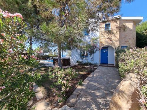 a house with a blue door and some trees at Olive Beach Villa in Peyia
