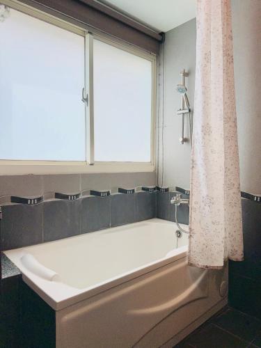a bath tub in a bathroom with a window at 杉羽松民宿-羅東運動公園落羽松 in Luodong