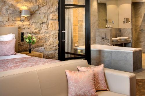 a bedroom with a bed and a tub and a sink at Domaine de la Klauss & Spa, Restaurant Gastronomique Le K in Montenach