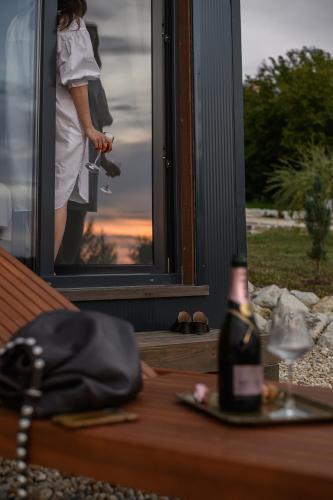 a woman standing outside a window with a bottle of wine at Casa Slarku - Luxury Container Houses in Miskolc