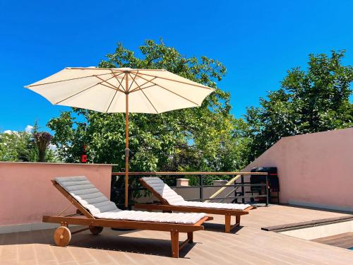 a patio with two lounge chairs and an umbrella at Pink House in Tsinandali