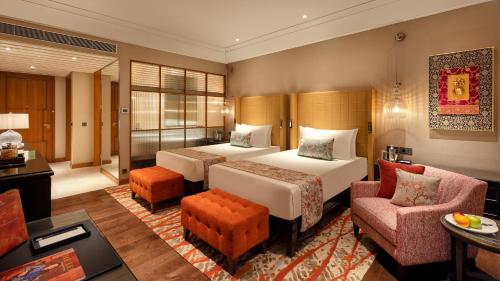 a hotel room with two beds and a couch at The Leela Hyderabad Banjara Hills in Hyderabad