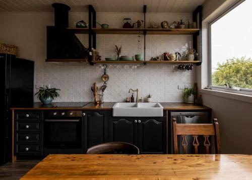 - une cuisine avec des placards noirs, un évier et une table dans l'établissement Luxury river cottage, gateway to the East Coast, à Avoca Tasmania