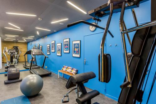 une salle de sport avec des murs bleus et des tapis de course dans l'établissement Appart'City Collection Paris Vélizy, à Vélizy-Villacoublay