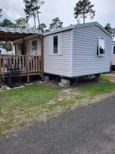 a tiny house with a porch and a deck at Mobil home contis lettes 40170 in Saint-Magne