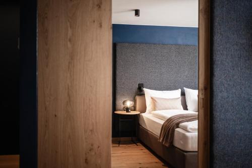 a bedroom with a bed with a blue headboard at The Post Mountain Residence in Dobbiaco