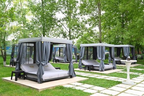 two gazebos in a park with trees at Multi Grand Pharaon Hotel in Yerevan