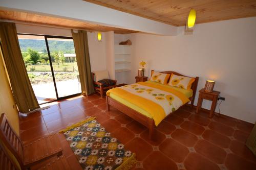 a bedroom with a bed and a large window at La Maravilla Lodge in Vilches