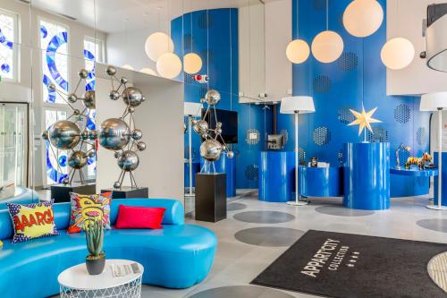 a living room with a blue couch and blue walls at Appart'City Collection Paris Vélizy in Vélizy-Villacoublay
