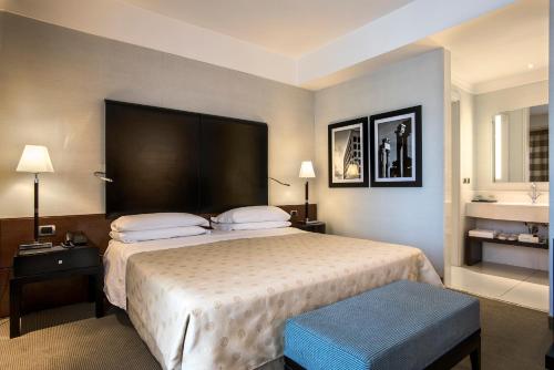 sypialnia z dużym łóżkiem z dużym zagłówkiem w obiekcie Ergife Palace Hotel w Rzymie