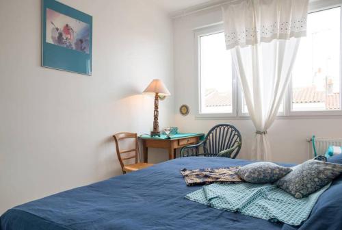 ein Schlafzimmer mit einem blauen Bett und einem Fenster in der Unterkunft À 2 pas de plage et commerces, jardin & parking in Les Sables-dʼOlonne