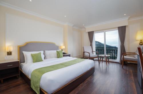 a hotel room with a large bed and a balcony at Preisha Hotel and Resorts in Gangtok