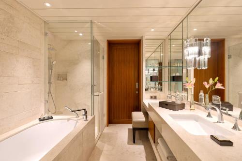 a bathroom with two sinks and a bath tub at The Leela Hyderabad Banjara Hills in Hyderabad
