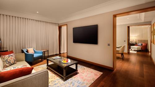 a living room with a couch and a tv at The Leela Hyderabad Banjara Hills in Hyderabad