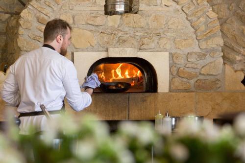 a man standing in front of a brick oven at Domaine de la Klauss & Spa, Restaurant Gastronomique Le K in Montenach