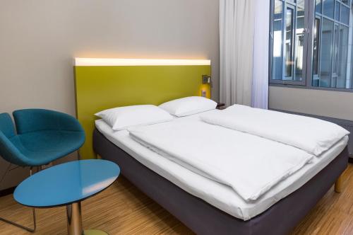 a bedroom with a bed and a blue chair at Comfort Hotel Kristiansand in Kristiansand