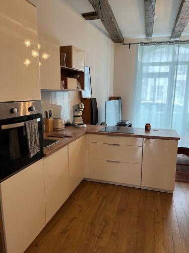 une cuisine avec des armoires blanches et un plancher en bois dans l'établissement Appartement Solidor 50m2 et jardin à deux pas des plages, à Saint-Malo