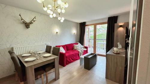 un salon avec une table et un canapé rouge dans l'établissement Crests Lodge - Plagne -Villages 2100m - Classé 4 étoiles, à La Plagne Tarentaise