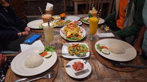 a wooden table with plates of food on it at Frangipani Inn & Restaurant in Seraya