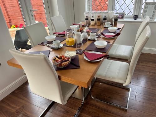 a wooden table with white chairs and a meal on it at Ragged Hall Lane in St. Albans