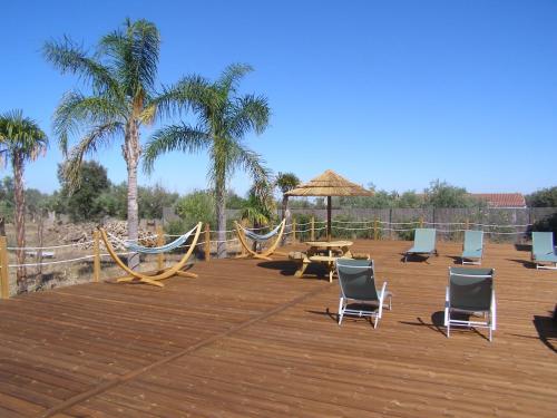 a deck with chairs and a hammock and palm trees at Quinta De Azemeis in Vimieiro