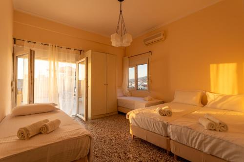 two beds in a room with two windows at Central Mytilene City-View Apartment for 7 in Mytilini