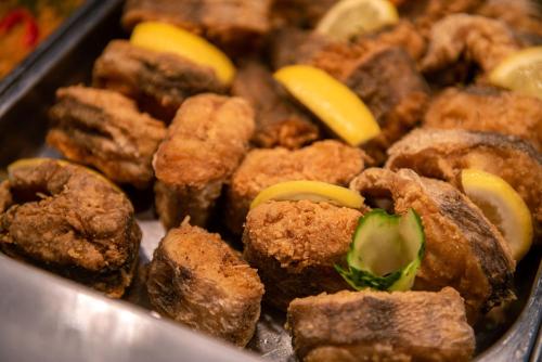 a tray of fried food with lemon slices on it at Hotel Doina in Neptun