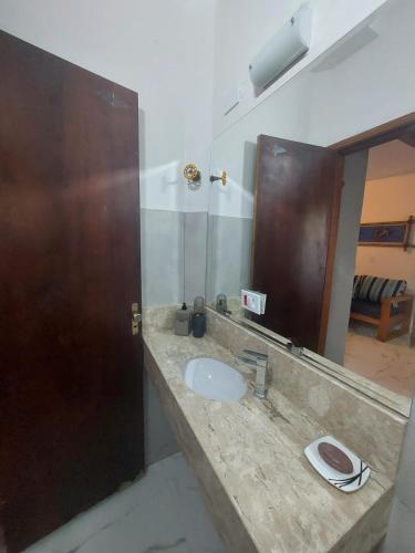 a bathroom with a sink and a large mirror at Flat Maresias in São Sebastião