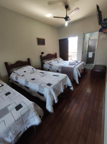 a group of three beds in a room at Café Palace Hotel in Três Pontas