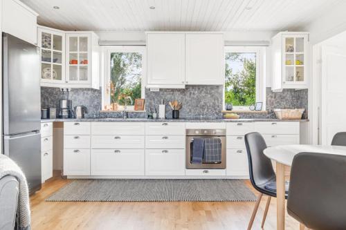 a kitchen with white cabinets and a table at Woodfield Cottage Skåne in Vollsjö