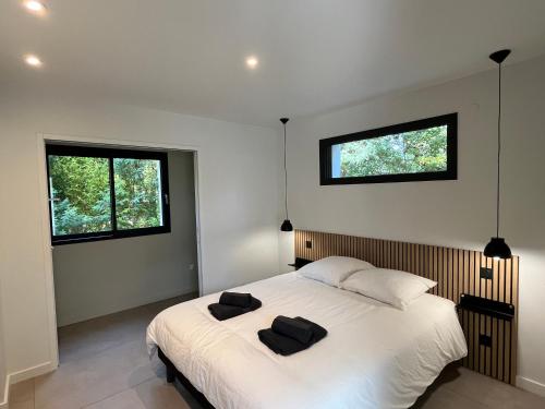 - une chambre avec un lit et 2 serviettes noires dans l'établissement Villas-des-oyats - Ophila - 8 personnes climatisée piscine chauffée, à Seignosse