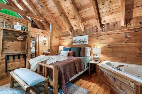 een slaapkamer in een blokhut met een bed en een badkuip bij Studio Log Cabin - hot tub, fireplace, views, private! in Pigeon Forge