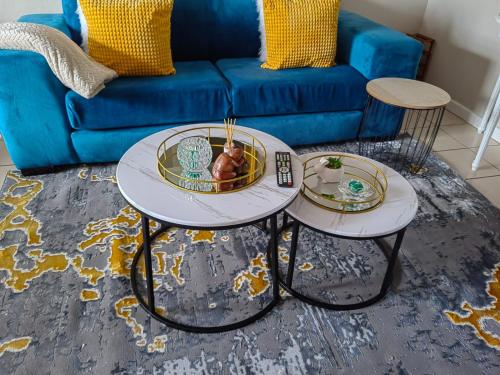 two tables in a living room with a blue couch at Tranquility facing Steyn City in Sandton