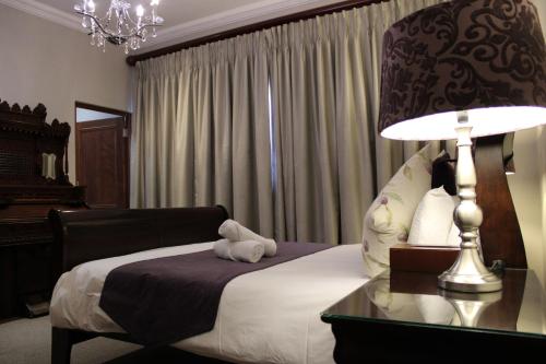 a bedroom with a bed and a table with a lamp at Abiento Guesthouse in Bloemfontein