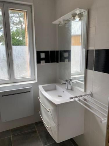 une salle de bain blanche avec un lavabo et un miroir dans l'établissement la maison Massonat, à Cossaye